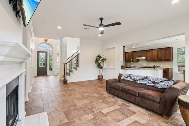 12404 Calistoga Way, Austin, TX 78732 - living area with stairs, a fireplace, light stone finish floors, ceiling fan, and recessed lighting
