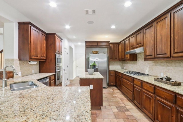 12404 Calistoga Way, Austin, TX 78732 - kitchen with appliances with stainless steel finishes, under cabinet range hood, decorative backsplash, light stone countertops, and recessed lighting
