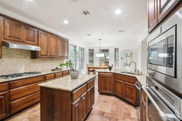 12404 Calistoga Way, Austin, TX 78732 - kitchen with appliances with stainless steel finishes, under cabinet range hood, tasteful backsplash, light stone countertops, and recessed lighting