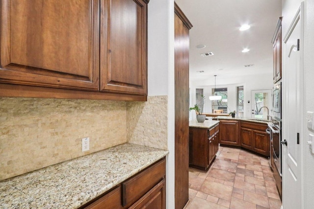 12404 Calistoga Way, Austin, TX 78732 - kitchen with tasteful backsplash, light stone counters, recessed lighting, light stone finish floors, and brown cabinets