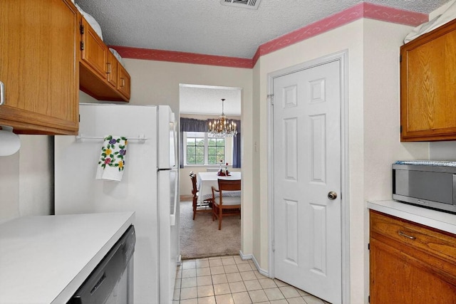 12062 Lincolnshire Dr, Austin, TX 78758 - kitchen with stainless steel microwave, freestanding refrigerator, light countertops, a chandelier, and a textured ceiling