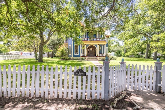 624 Saint Louis St, Gonzales, TX 78629 - view of front facade with a balcony, a porch, a fenced front yard, and a gate