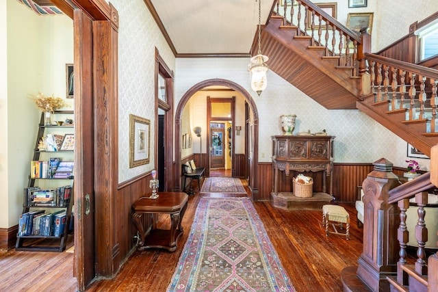 624 Saint Louis St, Gonzales, TX 78629 - hallway with wallpapered walls, hardwood / wood-style flooring, a wainscoted wall, arched walkways, and stairway