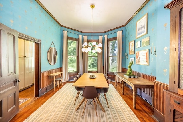 624 Saint Louis St, Gonzales, TX 78629 - dining space featuring wood finished floors, a chandelier, crown molding, a wainscoted wall, and wallpapered walls