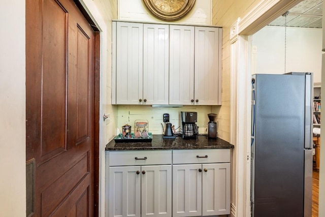 624 Saint Louis St, Gonzales, TX 78629 - kitchen with freestanding refrigerator, dark stone counters, and white cabinets