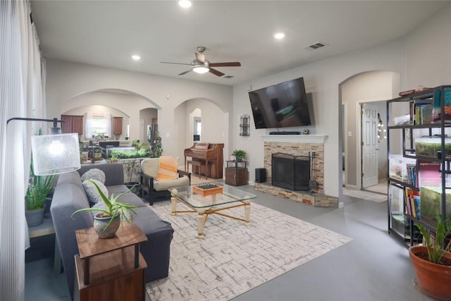 9213 Brents Elm Dr, Austin, TX 78744 - living room featuring ceiling fan, finished concrete flooring, arched walkways, a stone fireplace, and recessed lighting