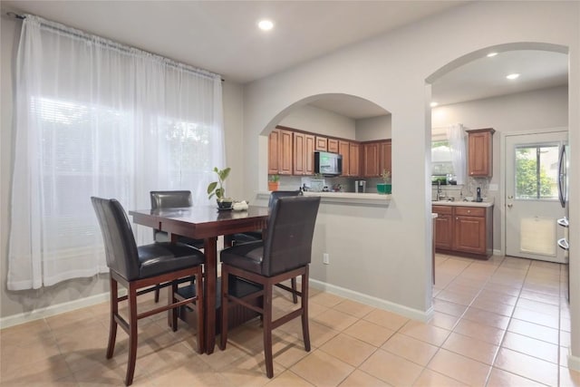 9213 Brents Elm Dr, Austin, TX 78744 - dining room featuring light tile patterned floors, recessed lighting, and arched walkways