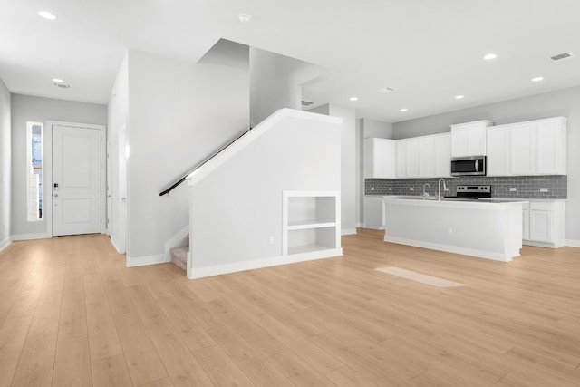 17507 Gitano Pass, Round Rock, TX 78664 - kitchen featuring stainless steel microwave, electric range oven, decorative backsplash, light countertops, and an island with sink