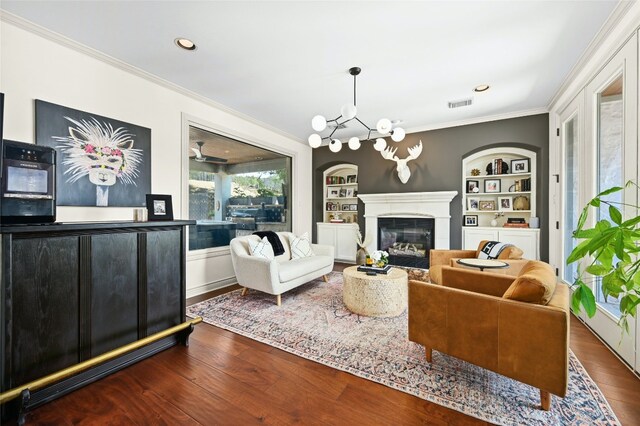 4332 Canoas Dr, Austin, TX 78730 - living room with crown molding, built in shelves, dark wood finished floors, a chandelier, and a glass covered fireplace