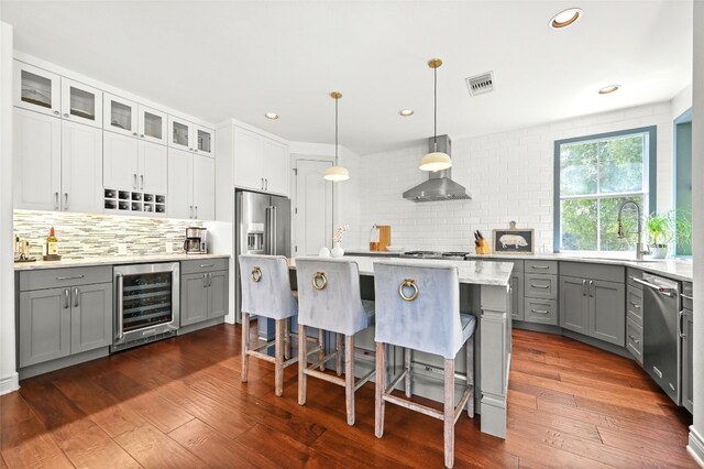 4332 Canoas Dr, Austin, TX 78730 - kitchen featuring beverage cooler, gray cabinetry, appliances with stainless steel finishes, wall chimney exhaust hood, and decorative backsplash