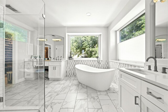 4332 Canoas Dr, Austin, TX 78730 - full bath with healthy amount of natural light, two vanities, recessed lighting, a freestanding tub, and a wainscoted wall