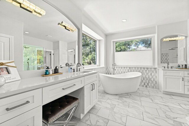 4332 Canoas Dr, Austin, TX 78730 - full bathroom featuring plenty of natural light, marble finish floors, vanity, a freestanding tub, and wainscoting