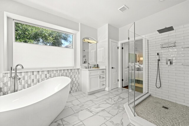 4332 Canoas Dr, Austin, TX 78730 - bathroom with marble look tiles, a shower stall, vanity, a freestanding tub, and wainscoting