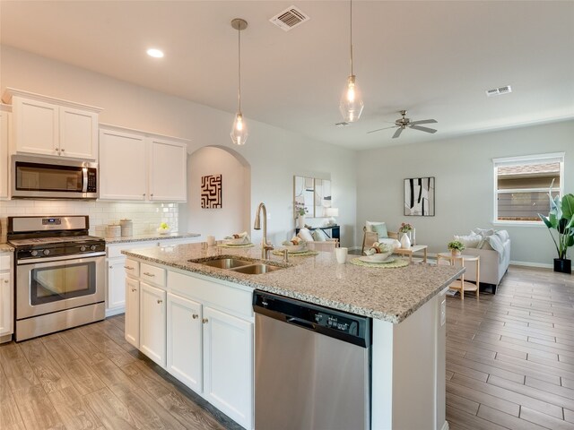 7816 Vista Mejor Dr, Austin, TX 78744 - kitchen featuring appliances with stainless steel finishes, open floor plan, arched walkways, backsplash, and light wood-type flooring