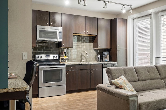 1900 Barton Springs Rd Unit 5033, Austin, TX 78704 - kitchen featuring appliances with stainless steel finishes, tasteful backsplash, dark brown cabinetry, light wood-style floors, and rail lighting