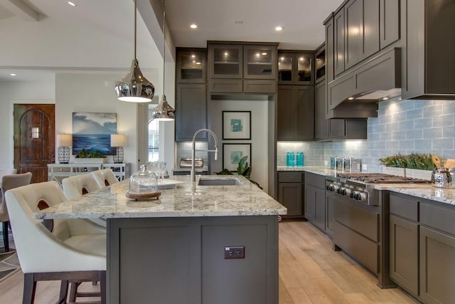 4106 Paleleaf Path, Bee Cave, TX 78738 - kitchen featuring light stone countertops, a breakfast bar area, tasteful backsplash, light wood-type flooring, and stainless steel gas cooktop