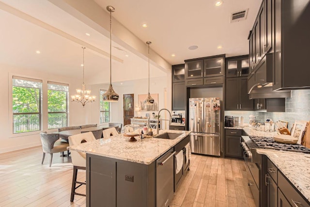 4106 Paleleaf Path, Bee Cave, TX 78738 - kitchen featuring stainless steel appliances, a kitchen breakfast bar, light wood-style floors, decorative backsplash, and light stone counters