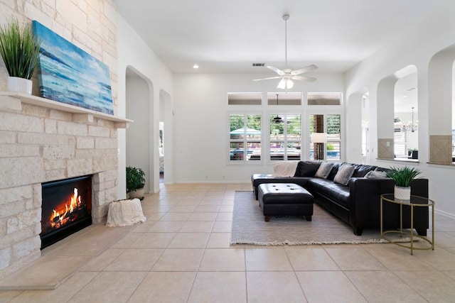 207 Dry Creek Rd, Austin, TX 78737 - living room with light tile patterned floors, ceiling fan, a stone fireplace, and arched walkways
