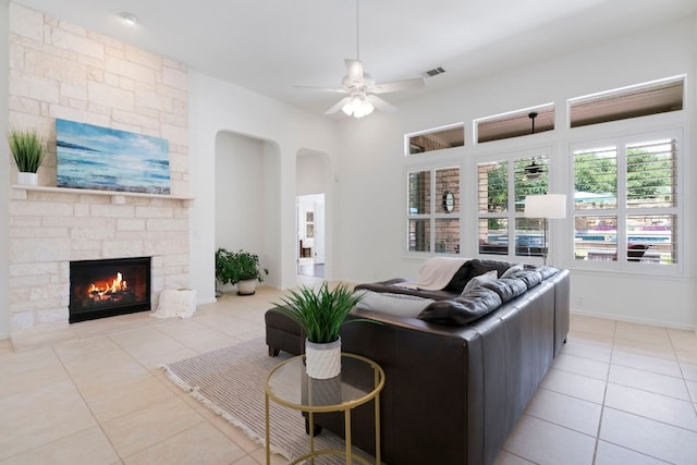 207 Dry Creek Rd, Austin, TX 78737 - living area featuring light tile patterned floors, a ceiling fan, a stone fireplace, and arched walkways