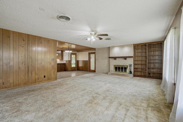 3012 Hunt Trl, Austin, TX 78757 - unfurnished living room with a brick fireplace, ceiling fan, a textured ceiling, wooden walls, and carpet