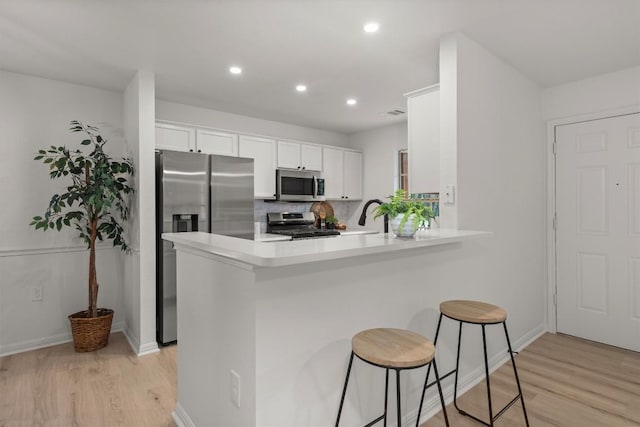 6516 Garden View Dr, Austin, TX 78724 - kitchen with stainless steel appliances, light wood finished floors, a kitchen bar, light countertops, and a peninsula