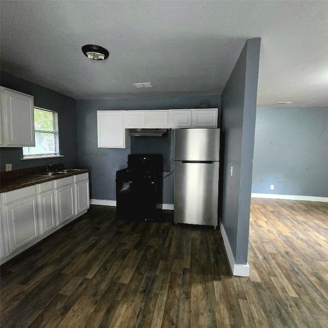 1403 S Salina St W, Austin, TX 78702 - kitchen with freestanding refrigerator, black gas range, dark wood-style flooring, white cabinetry, and range hood