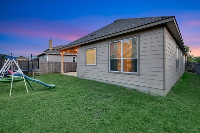 806 Thrasher Glade Dr, Pflugerville, TX 78660 - back of property at dusk featuring a trampoline, a fenced backyard, and roof with shingles