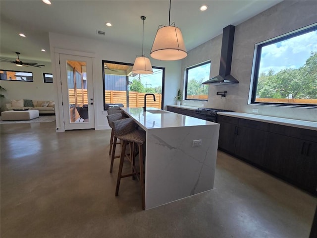 5301 Grover Ave, Austin, TX 78756 - kitchen featuring wall chimney range hood, concrete flooring, recessed lighting, a breakfast bar area, and a center island with sink
