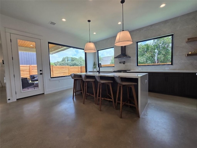 5301 Grover Ave, Austin, TX 78756 - kitchen with light countertops, finished concrete floors, wall chimney range hood, a kitchen island with sink, and recessed lighting