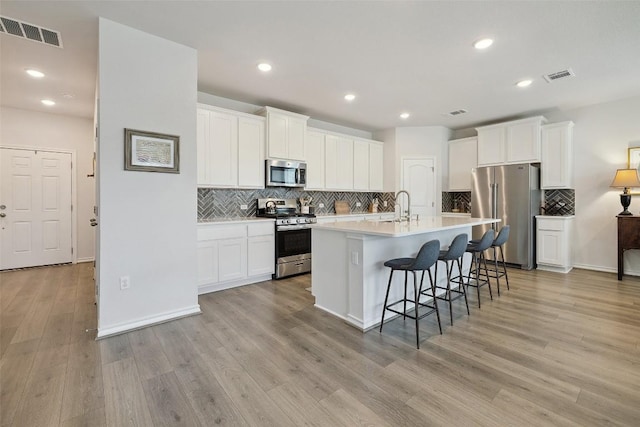 3003 Salvidar Bnd, Austin, TX 78728 - kitchen featuring appliances with stainless steel finishes, backsplash, white cabinets, light wood-style flooring, and recessed lighting