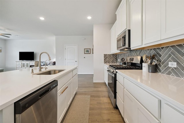 3003 Salvidar Bnd, Austin, TX 78728 - kitchen with stainless steel appliances, decorative backsplash, white cabinetry, light countertops, and light wood finished floors
