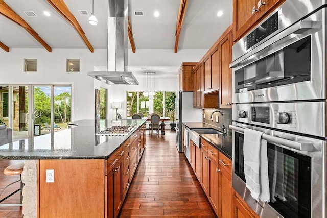 179 Sandy Creek Cv, Driftwood, TX 78619 - kitchen featuring beamed ceiling, island range hood, stainless steel appliances, a center island, and a breakfast bar area