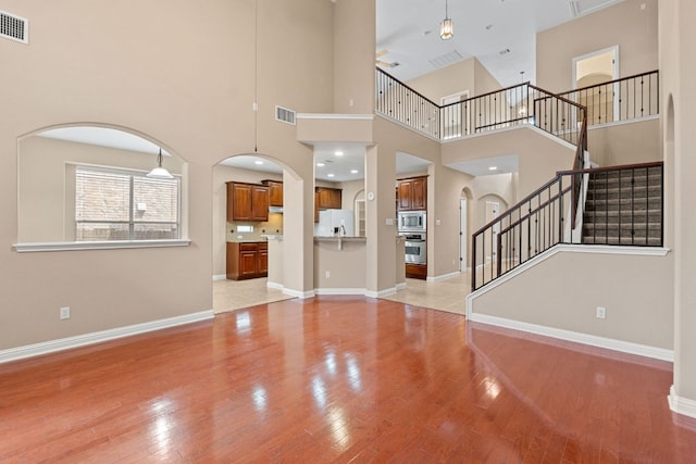 829 Zappa Dr, Cedar Park, TX 78613 - unfurnished living room featuring arched walkways, light wood finished floors, stairway, and a towering ceiling