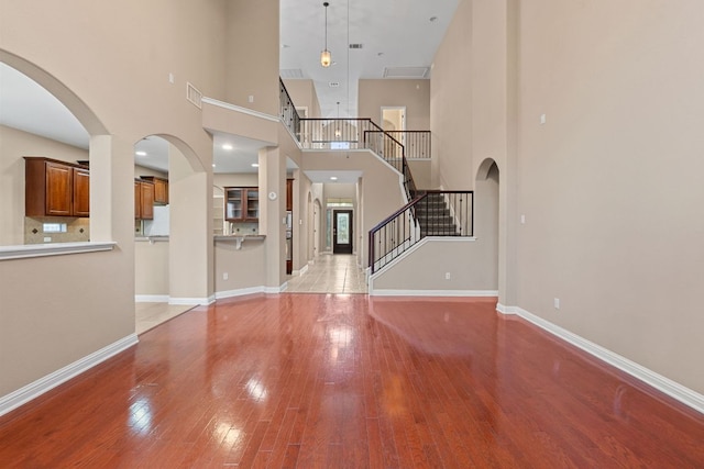829 Zappa Dr, Cedar Park, TX 78613 - unfurnished living room with light wood-type flooring, stairs, a high ceiling, and arched walkways