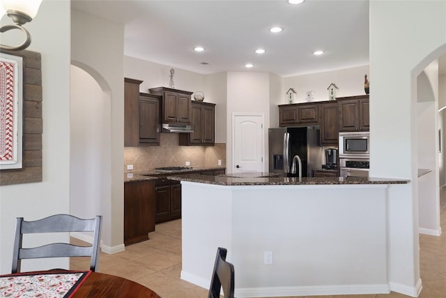 3204 Herrero Path, Cedar Park, TX 78641 - kitchen with appliances with stainless steel finishes, arched walkways, dark brown cabinetry, dark stone counters, and recessed lighting