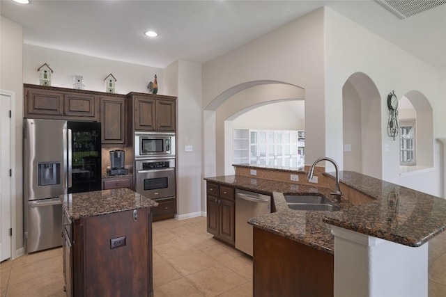 3204 Herrero Path, Cedar Park, TX 78641 - kitchen with stainless steel appliances, a center island with sink, dark stone countertops, light tile patterned floors, and recessed lighting