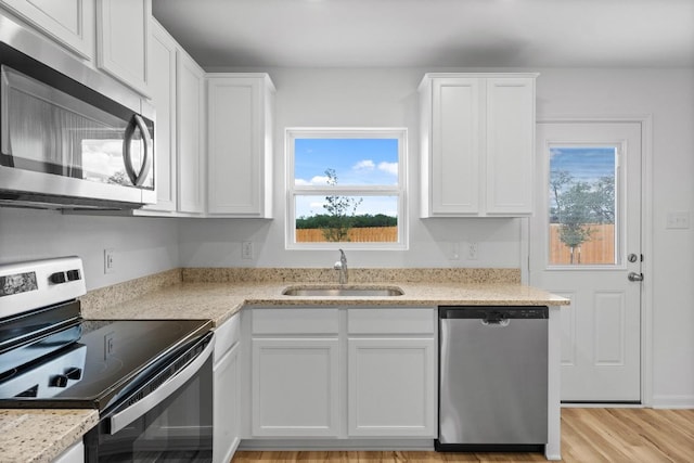 524 Aplite Pass, Maxwell, TX 78656 - kitchen featuring appliances with stainless steel finishes, white cabinetry, light wood-type flooring, and light stone counters