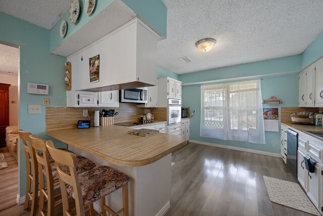 1121 Nola Ruth Blvd, Harker Heights, TX 76548 - kitchen with stainless steel appliances, a textured ceiling, backsplash, white cabinets, and wood finished floors