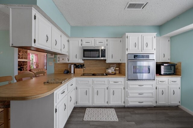 1121 Nola Ruth Blvd, Harker Heights, TX 76548 - kitchen with stainless steel appliances, a peninsula, a textured ceiling, tasteful backsplash, and white cabinetry