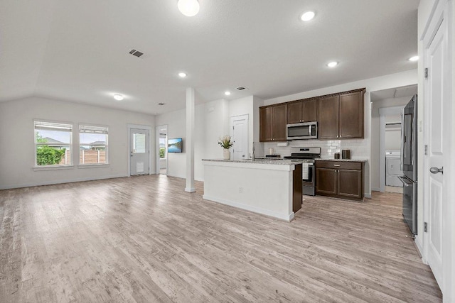 136 Gidran Trl, Georgetown, TX 78626 - kitchen with appliances with stainless steel finishes, light wood-style flooring, dark brown cabinets, open floor plan, and an island with sink
