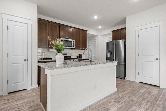 136 Gidran Trl, Georgetown, TX 78626 - kitchen featuring stainless steel appliances, dark brown cabinets, backsplash, light wood-style floors, and light stone countertops