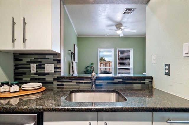 2804 Rio Grande St Unit 211, Austin, TX 78705 - kitchen featuring decorative backsplash, ceiling fan, crown molding, dark stone counters, and white cabinets