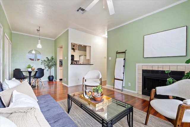 2804 Rio Grande St Unit 211, Austin, TX 78705 - living area featuring wood finished floors, a ceiling fan, ornamental molding, and a tiled fireplace