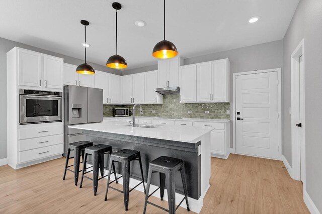 800 Sand Hill Branch Dr Unit 38, Austin, TX 78748 - kitchen with appliances with stainless steel finishes, a kitchen breakfast bar, light wood-type flooring, white cabinetry, and tasteful backsplash