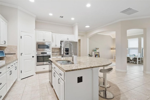 2508 Outlook Ridge Loop, Leander, TX 78641 - kitchen with stainless steel appliances, arched walkways, backsplash, a breakfast bar area, and ornamental molding