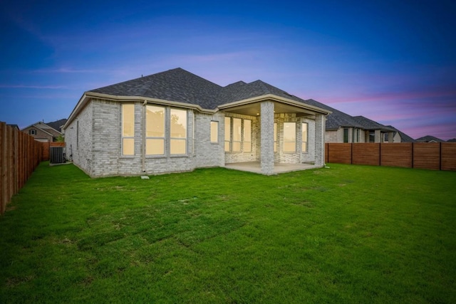 2113 Tobiano Trce, Georgetown, TX 78633 - back of house at dusk featuring a patio, a fenced backyard, brick siding, and roof with shingles