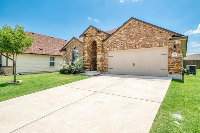125 Lillian Dr, Taylor, TX 76574 - view of front facade featuring an attached garage, concrete driveway, a front lawn, stone siding, and brick siding