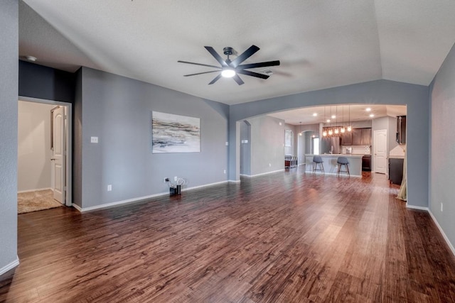 125 Lillian Dr, Taylor, TX 76574 - unfurnished living room with arched walkways, ceiling fan, dark wood finished floors, and a chandelier