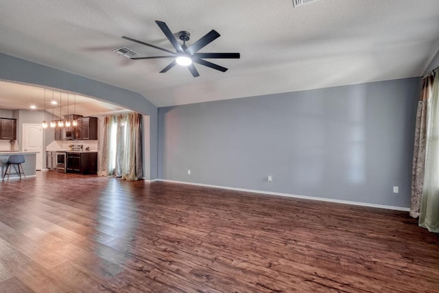 125 Lillian Dr, Taylor, TX 76574 - unfurnished living room featuring dark wood-style floors, a ceiling fan, lofted ceiling, arched walkways, and a chandelier
