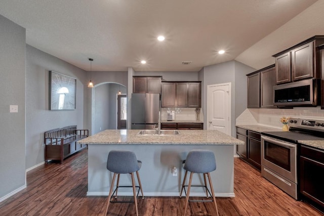 125 Lillian Dr, Taylor, TX 76574 - kitchen featuring appliances with stainless steel finishes, arched walkways, backsplash, an island with sink, and recessed lighting